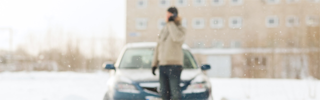 Mężczyzna stoi przed samochodem na śniegu.