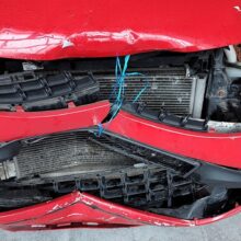 Obraz czerwonego samochodu z uszkodzoną maską.